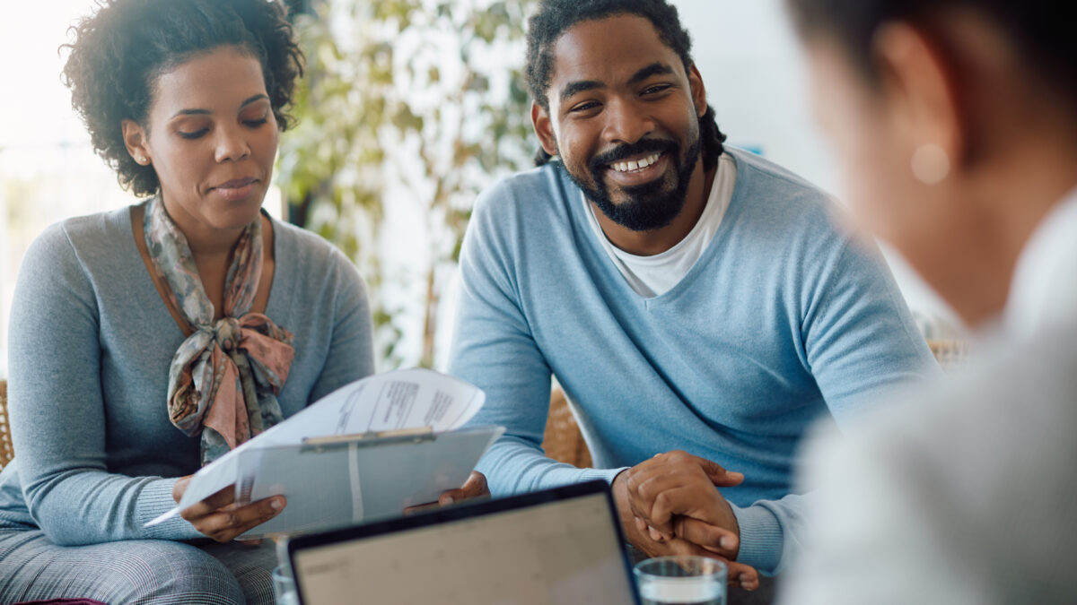 Happy black couple goes through paperwork while buying a home.