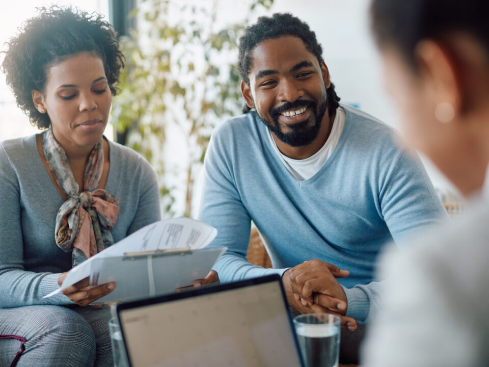 Happy black couple goes through paperwork while buying a home.