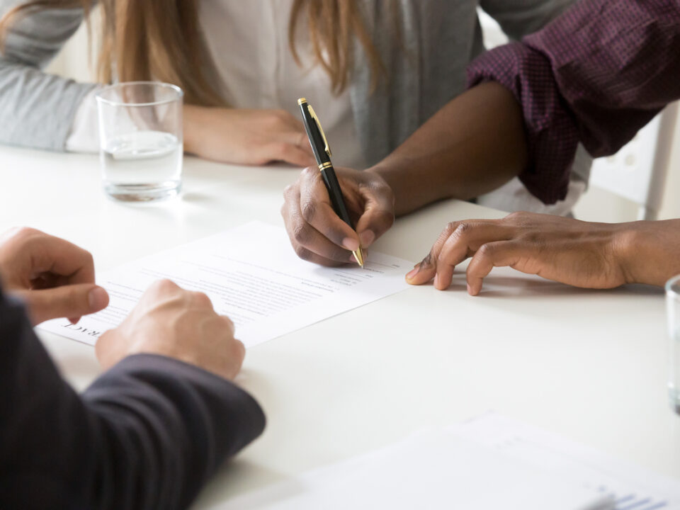 Close up of a couple signing contract for property purchase