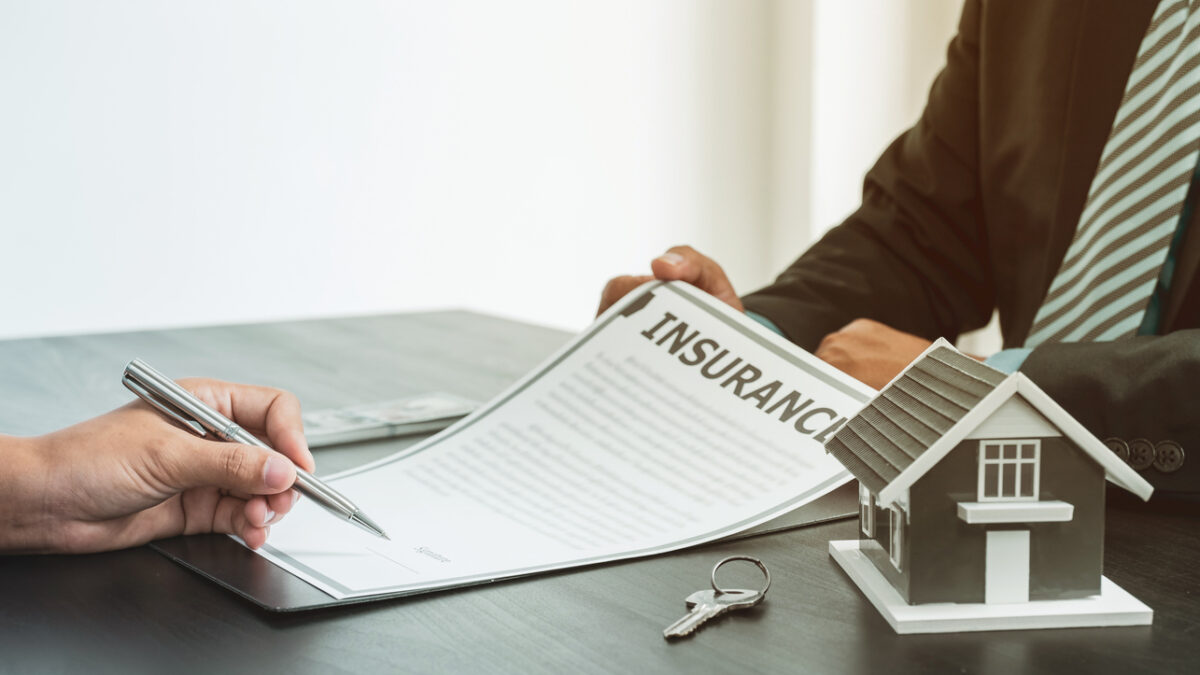 a hand holding a pen to sign an insurance form